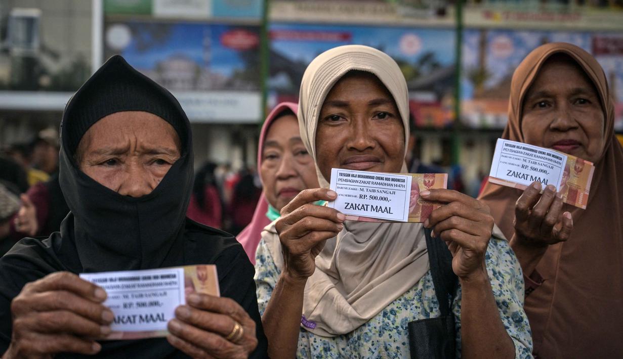 Jumlah ini naik 100 persen dibandingkan tahun lalu yang tercatat sekitar 16 ribu penerima. Guna menghindari penumpukan warga, penyaluran dilakukan secara bertahap selama 12 hari. Tampak dalam foto, warga memperlihatkan uang hasil pembagian zakat di Masjid Cheng Hoo, Surabaya, Jawa Timur pada Rabu 4 Maret 2026. (JUNI KRISWANTO/AFP)