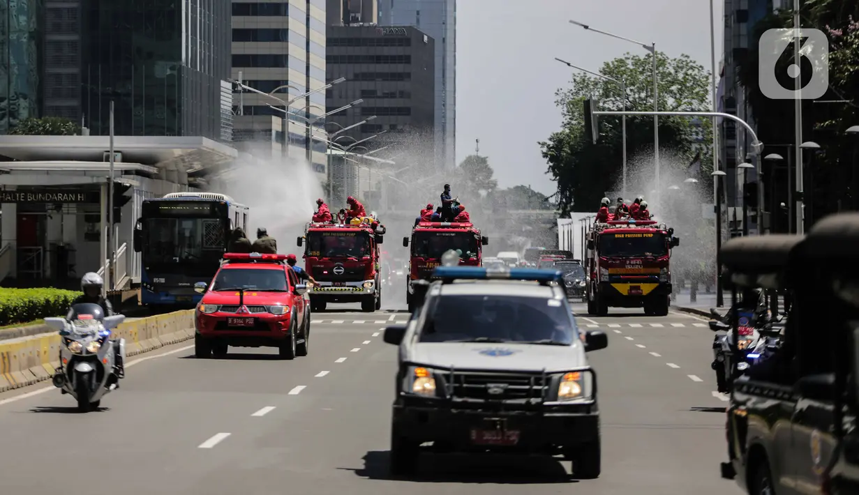 Mobil pemadam dari Dinas Pemadam Kebakaran Pemprov DKI melakukan penyemprotan cairan disinfektan di Jalan Thamrin, Jakarta, Selasa (31/3/2020). Penyemprotan yang dilakukan terus menerus itu untuk meminimalisir penyebaran COVID-19 di ruang udara dan ruas jalan. (Liputan6.com/Faizal Fanani)