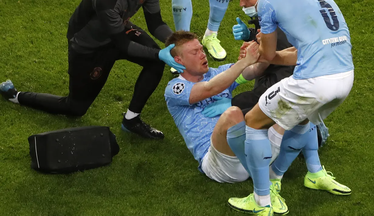 Kevin De Bruyne (tengah) dibantu untuk bangun setelah menjalani perawatan karena tabrakan dengan Antonio Rudiger selama pertandingan final Liga Champions antara Manchester City dan Chelsea di Stadion Dragao di Porto, Portugal, Sabtu (29/05/2021) atau Minggu dini hari WIB. (Foto: AP/Pool/Susana Vera)
