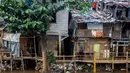 Kepadatan yang sangat tinggi ini disebabkan oleh faktor urbanisasi yang terus meningkat, menjadikan Jakarta sebagai pusat ekonomi dan bisnis nasional. Tampak dalam foto, seorang pria berdiri di atas jembatan bambu yang menghubungkan rumah-rumah di permukiman kumuh tepi sungai yang padat penduduk di Jakarta pada Selasa 21 April 2026. (BAY ISMOYO/AFP)