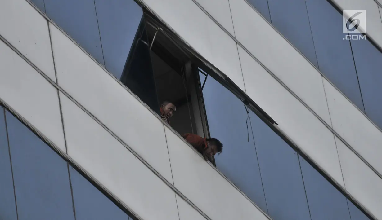 Dua petugas pemadam terlihat di jendela gedung saat proses pendinginan pasca kebakaran di Kantor Kementerian Perhubungan, Jakarta, Minggu (8/7). Dalam kebakaran tersebut dilaporkan 3 orang tewas. (Merdeka.com/Iqbal S Nugroho)