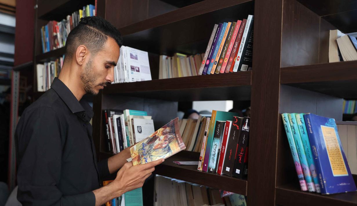 Perpustakaan ini menjadi ruang aman bagi anak-anak dan warga terdampak konflik untuk tetap bisa membaca dan belajar, terutama setelah banyak fasilitas pendidikan hancur. Tampak dalam foto, seorang pengungsi Palestina membaca buku di perpustakaan Al-Ankaa (Phoenix), perpustakaan pertama yang dibuka sejak gencatan senjata di Jalur Gaza yang berisi buku-buku yang diselamatkan dari perpustakaan yang hancur selama perang Israel-Hamas, di lingkungan Rimal, Kota Gaza pada Selasa 21 April 2026. (Omar AL-QATTAA/AFP)
