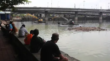 Warga menyaksikan proses pengerukan Waduk Grogol, Jakarta, Senin (9/4). Pengerukan dilakukan guna meningkatkan daya tampung waduk sebagai bagian dari upaya mengatasi banjir. (Liputan6.com/Arya Manggala)