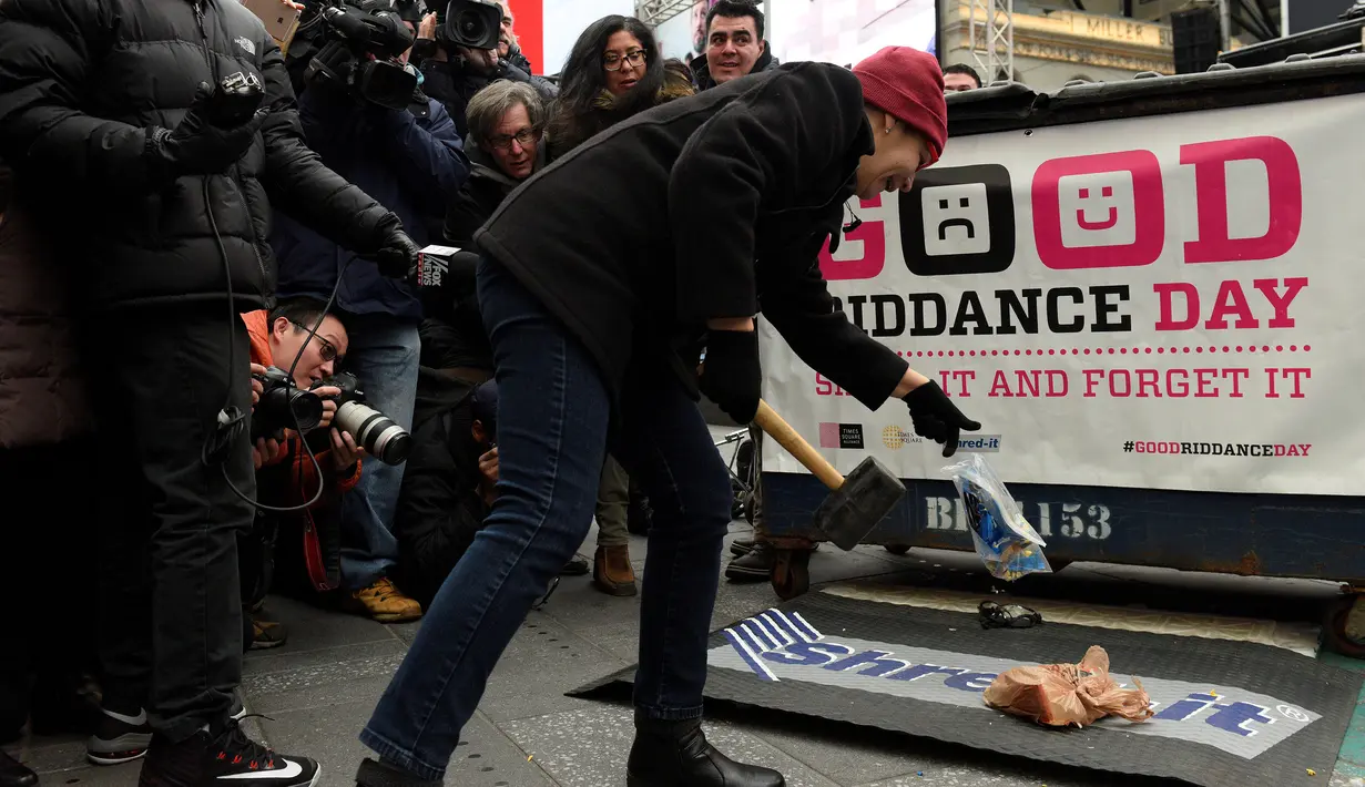 Seorang wanita melemparkan barang miliknya untuk dihancurkan dalam acara "Good Riddance Day" di Times Square, New York, Rabu (28/12). Good Riddance Day menjadi tradisi warga New York menghapus kenangan buruk selama satu tahun. (REUTERS/Darren Ornitz)