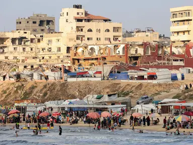 Warga Palestina berkumpul di pantai, kota Gaza untuk menghindari panas dan tenda pengungsian di tengah perang yang sedang berlangsung antara Israel dan milisi Hamas pada 8 Juni 2025. (Omar AL-QATTAA/AFP)