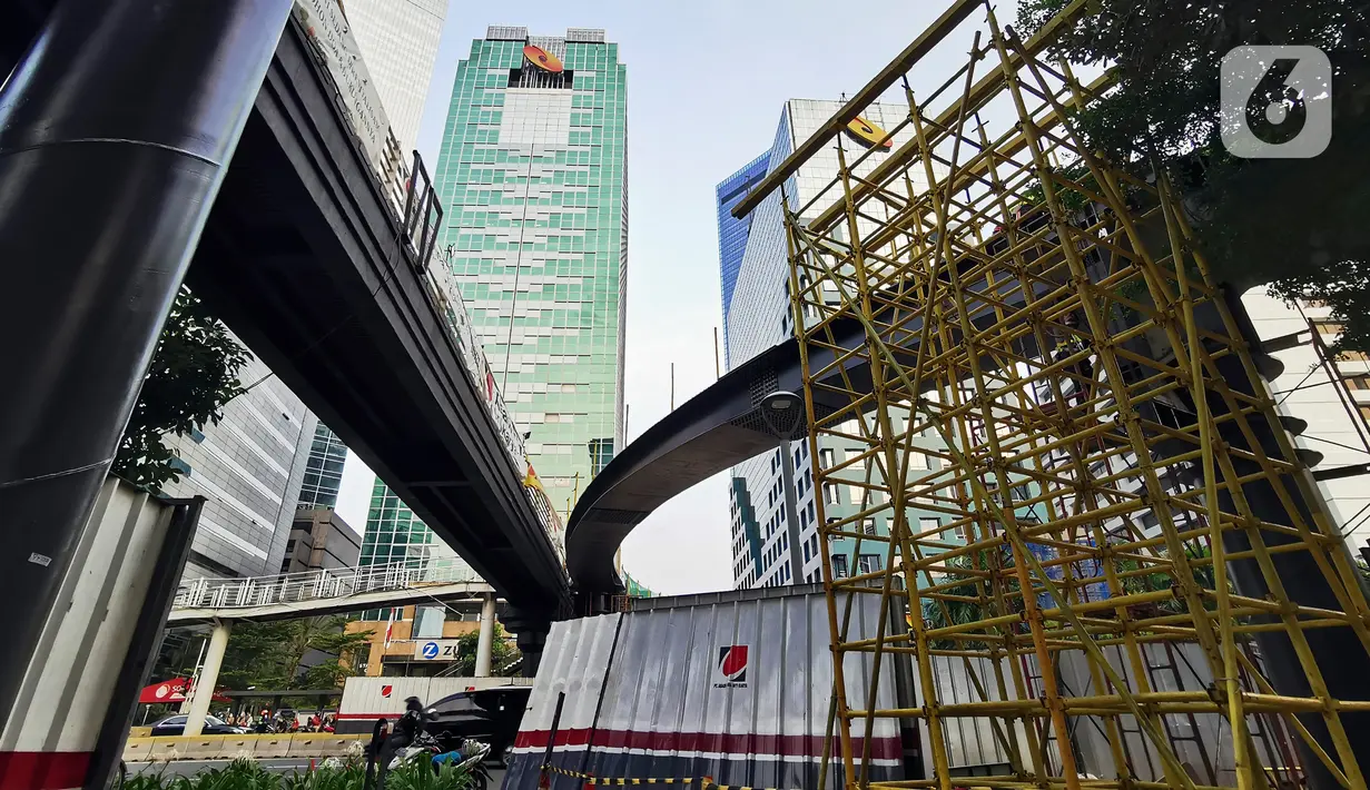 Pekerja menyelesaikan pengerjaan jembatan penyeberangan orang (JPO) dan jembatan penyeberangan sepeda di Karet Sudirman, Jakarta, Jumat (8/10/2021). JPO yang akan dilengkapi jalur sepeda dan terintegrasi dengan halte Transjakarta itu akan rampung pada November 2021. (Liputan6.com/Johan Tallo)