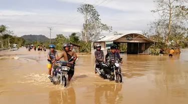 Pengendara sepeda motor melintasi jalan raya yang banjir usai terjangan topan Phanfone di Ormoc City, Provinsi Leyte, Filipina, Rabu (25/12/2019). Topan membuat jutaan warga di negara yang mayoritas beragama Katolik itu merayakan Natal dengan kesedihan. (RONALD FRANK DEJON/AFP)