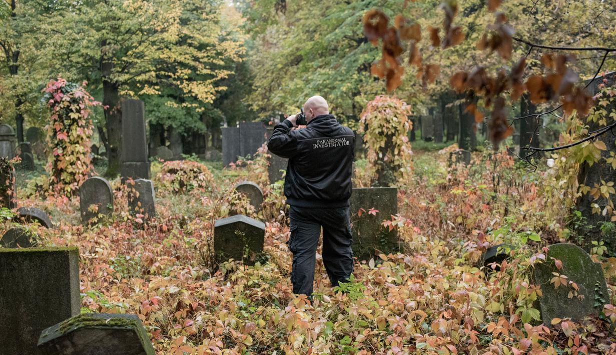 Pemburu hantu "Paranormal Investigator" menelusuri batu nisan saat mencari aktivitas gaib di pusat pemakaman tua di Wina, Austria, 20 Oktober 2016. Pemakaman ini disinyalir memiliki aura mistis yang kental dengan aktivitas makhluk halus. (JOE KLAMAR/AFP)