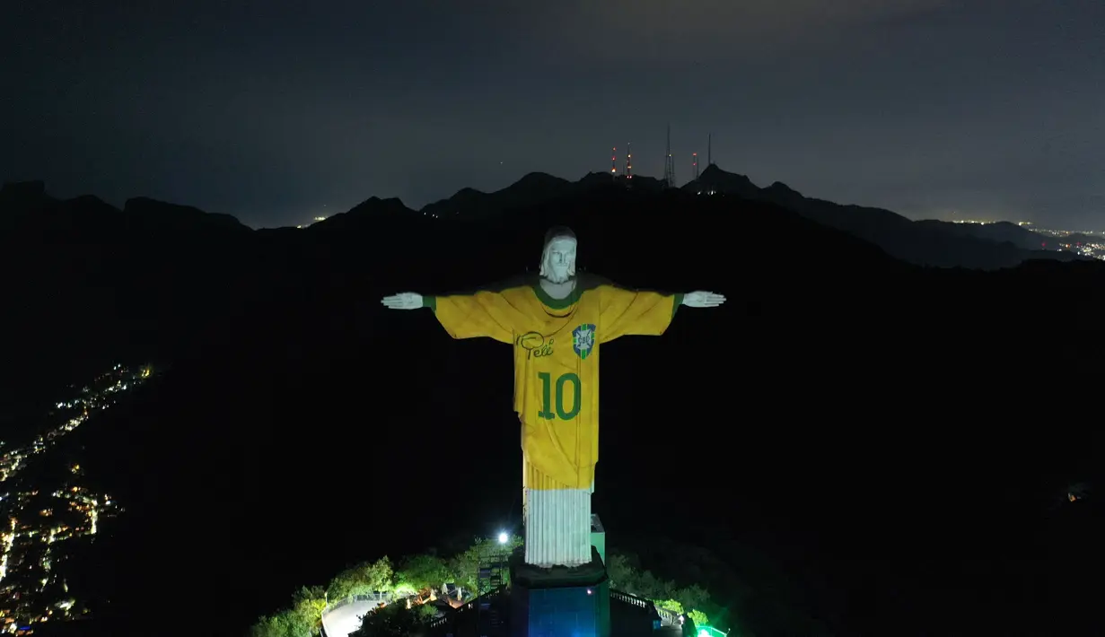 Patung Kristus Sang Penebus (Christ the Redeemer) di Rio de Janeiro, Brasil diterangi gambar jersey dari legenda sepak bola Brasil, Pele sebagai penghormatan atas satu tahun kematian sang pemain pada Jumat, 29 Desember 2023. (AFP/Mauro Pimentel)