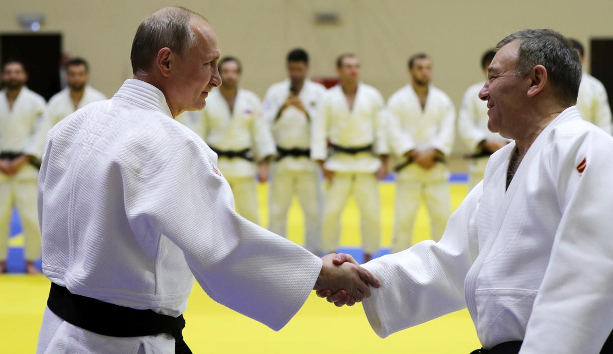 Presiden Rusia, Vladimir Putin menyapa pelatih sebelum mengikuti latihan judo bersama atlet nasional Rusia di Sochi, Kamis (14/2). Judo merupakan salah satu olahraga kegemaran Putin yang telah digeluti sejak masa muda. (Mikhail KLIMENTYEV/SPUTNIK/AFP)