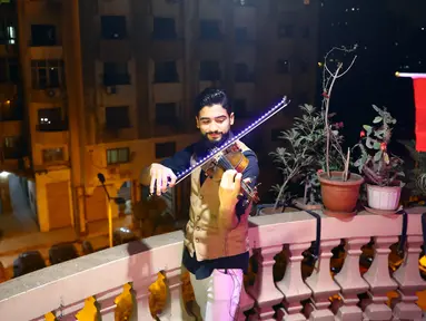 Pemain biola asal Mesir Mohammed Adel membawakan konser biola dari atas balkon di Kairo, pada 31 Maret 2020. Setiap malam, pemain biola itu menampilkan konser langsung dari balkonnya untuk menghibur para tetangganya selama jam malam nasional yang diberlakukan akibat COVID-19. (Xinhua/Ahmed Gomaa)