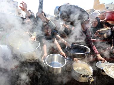 Warga Palestina mengulurkan panci kosong di depan dapur amal untuk menerima makanan matang, di Kota Gaza pada 23 Agustus 2025. (Omar AL-QATTAA/AFP)
