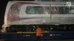 Pekerja mengecek gerbong kereta ringan/Light Rail Transit (LRT) yang baru tiba di Pelabuhan Car Terminal, Tanjung Priok, Jakarta, Jumat (13/4).  Dua gerbong kereta LRT yang diangkut itu merupakan yang pertama tiba di Jakarta. (Merdeka.com/Imam Buhori)