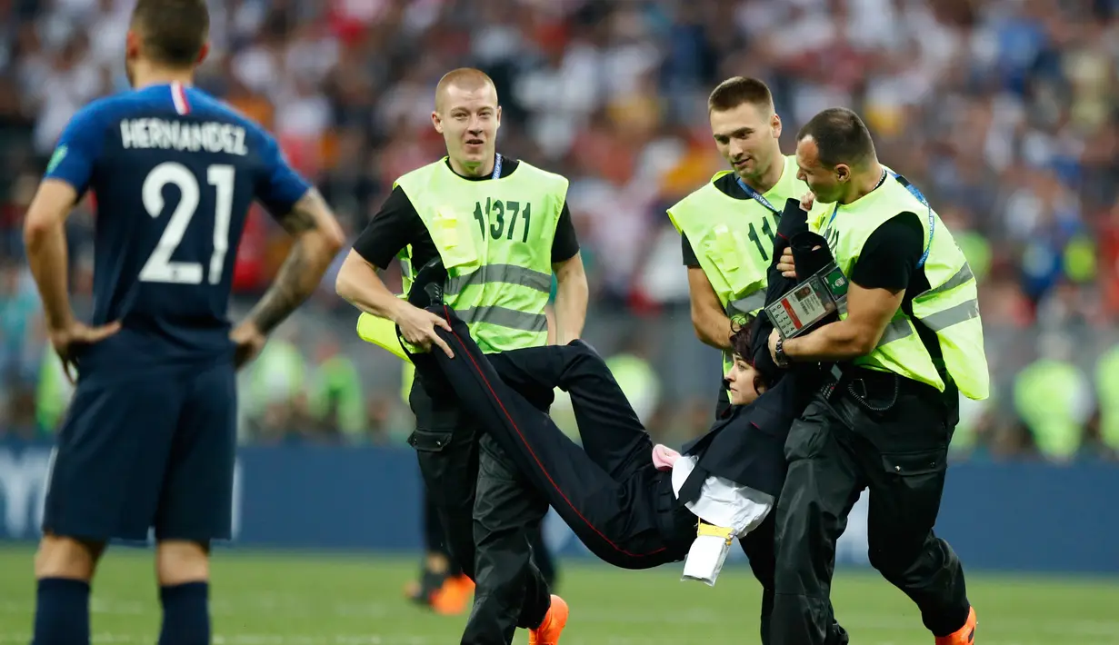 Petugas mengamankan seorang wanita yang menyusup masuk ke lapangan pada laga final Piala Dunia 2018 antara Prancis dan Kroasia di Luzhniki Stadium, Minggu (15/7). Grup band anti-Kremlin mengaku sebagai penyusup laga final itu. (AP/Matthias Schrader)