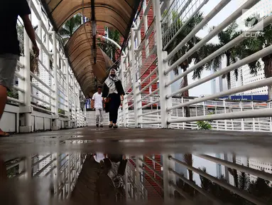 Warga melintasi Jembatan Penyeberangan Orang (JPO) yang rusak di kawasan Dukuh Atas, Jakarta, Rabu (12/12). Rusaknya JPO membahayakan pejalan kaki yang melinatas karena jembatan menjadi licin saat hujan. (Liputan6.com/JohanTallo)