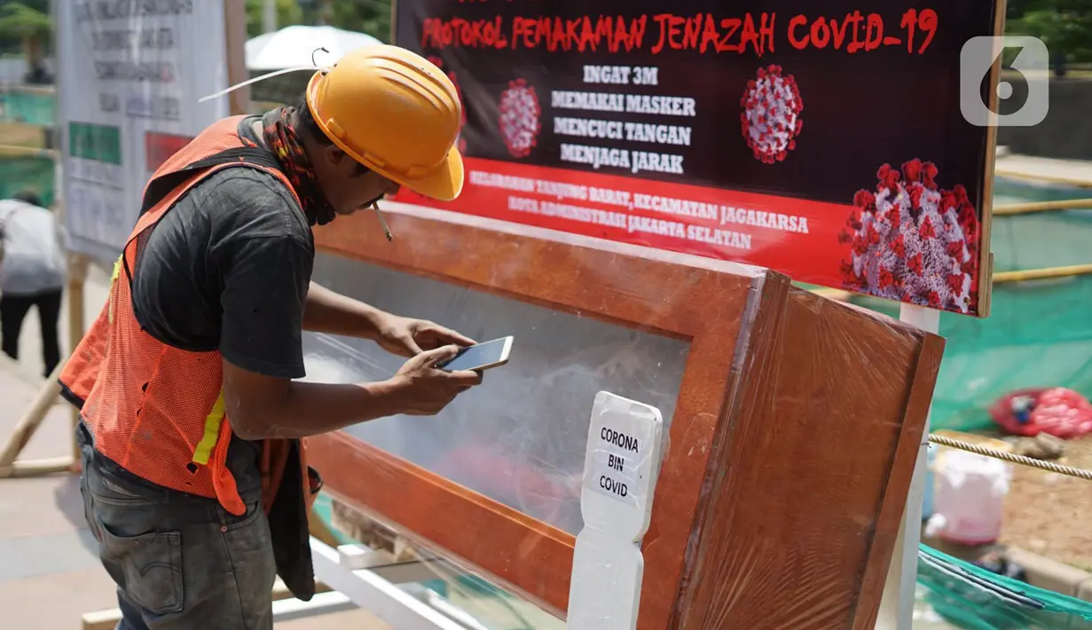 Pekerja mengambil gambar peti mati berisi jenazah korban COVID-19 di kawasan Tanjung Barat, Jakarta, Sabtu (5/9/2020). Pemerintah terus melakukan kampanye peringatan bahaya COVID-19 bagi masyarakat guna menekan angka positif dan kematian akibat virus tersebut. (Liputan6.com/Immanuel Antonius)