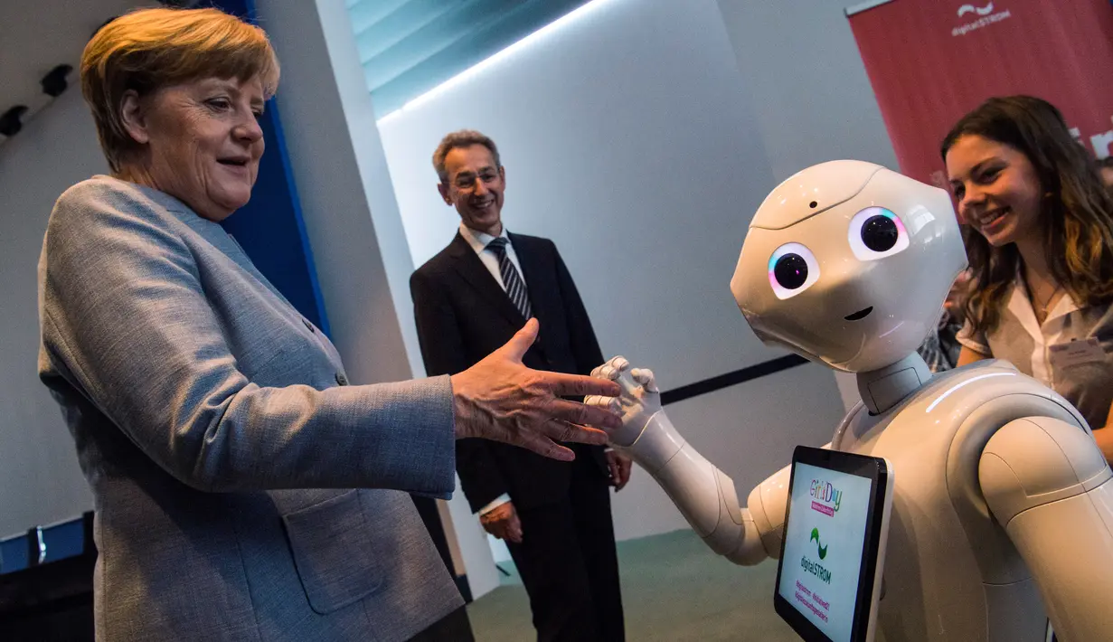 Kanselir Jerman Angela Merkel disapa robot interaktif di stand digitalSTROM selama pameran Girl's Day di Berlin, Rabu (26/4). Pameran ini bertujuan menarik wanita muda untuk menggeluti pekerjaan hi-tech dan engineering. (AFP PHOTO / John MACDOUGALL)
