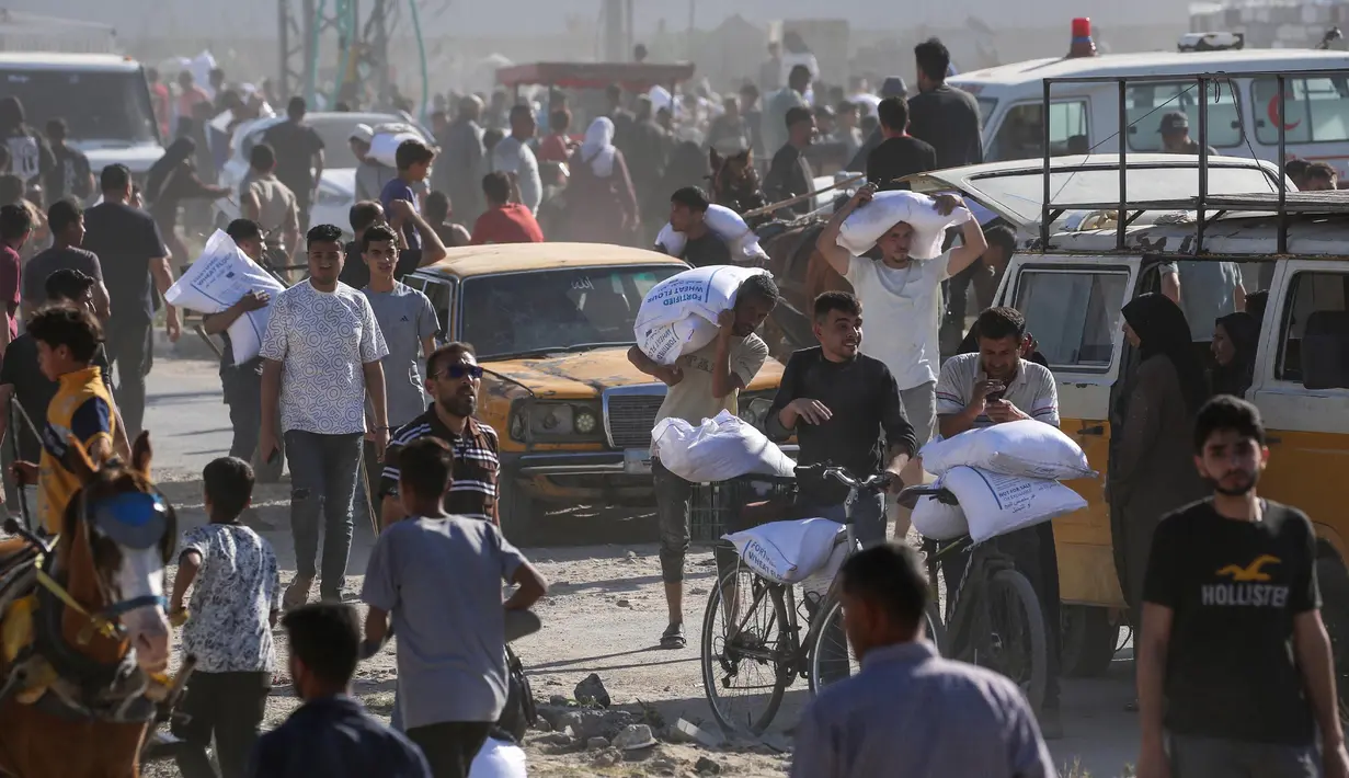 Para pengungsi Palestina mengangkut kantong-kantong bantuan makanan setelah menyerbu gudang Program Pangan Dunia di Deir el-Balah di Jalur Gaza tengah pada 28 Mei 2025. (Eyad BABA/AFP)