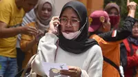Seorang wanita melakukan panggilan telepon sambil memegang foto korban kerusuhan Stadion Kanjuruhan menangis saat menunggu di Rumah Sakit Saiful Anwar, Malang, Jawa Timur, Minggu (2/10/2022). Hingga saat ini, dilaporkan sebanyak 129 orang meninggal dunia dalam kejadian tersebut. (AP Photo/Trisnadi)