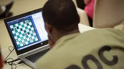 Seorang narapidana Cook County serius memperhatikan laptop saat bertanding catur melawan Penjara Viana dari Brasil di Chicago, Illinois (17/5). Ini ketiga kalinya kompetisi catur internasional untuk para narapidana digelar. (Scott Olson/Getty Images/AFP)