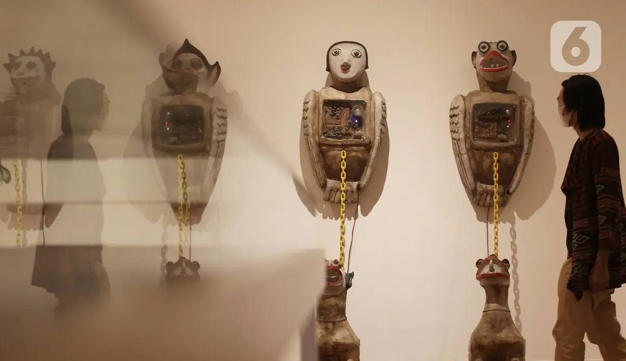 Pengunjung melintasi karya seni yang ditampilkan dalam Pameran Tetap Galeri Nasional Indonesia di Galeri Nasional, Jakarta, Kamis (28/10/2021). Galeri Nasional resmi membuka ruang pamerannya untuk masyarakat umum mulai seiring diberlakukannya PPKM level dua di DKI . (Liputan6.com/Herman Zakhria)