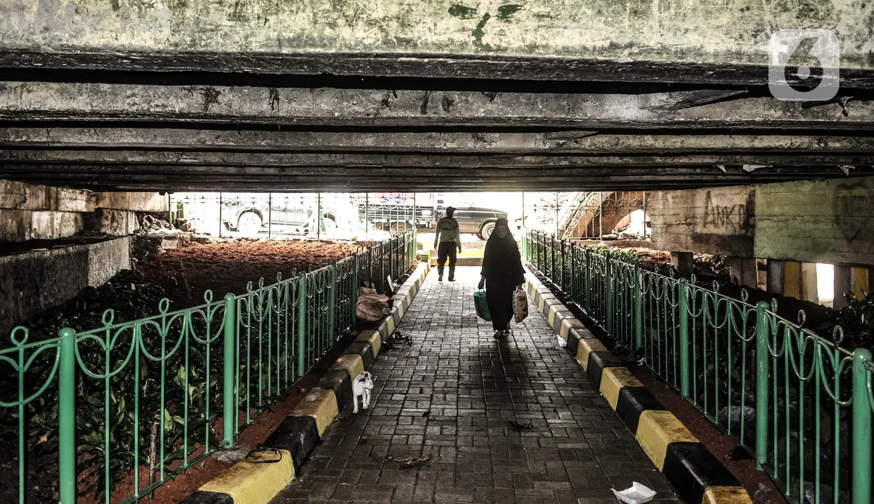 Warga berjalan melintasi taman yang sedang dibangun di kolong Jembatan Pegangsaan, Jakarta, Selasa (19/1/2021). Selain menjadi area interaksi warga sekitar, pembangunan taman di kolong jembatan tersebut untuk mempercantik kawasan bantaran kali. (merdeka.com/Iqbal S. Nugroho)