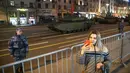 Seorang wanita berswafoto saat kendaraan militer bersiap meluncur di sepanjang Jalan Tverskaya menuju Lapangan Merah saat latihan parade militer Hari Kemenangan di Moskow, Rusia, Kamis (29/4/2021). Pawai digelar untuk merayakan 76 tahun kemenangan Rusia di PD II. (AP Photo/Pavel Golovkin)