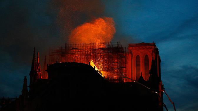 Petugas pemadam kebakaran berusaha memadamkan api dari Gereja Katedral Notre-Dame di kota Paris, Prancis, pada Senin (15/4). Katedral ini termasuk salah satu gereja roman katolik yang terkenal di seluruh dunia dengan luas total bangunanya mencapai 6.144 meter persegi. (AP Photo/Francois Mori)