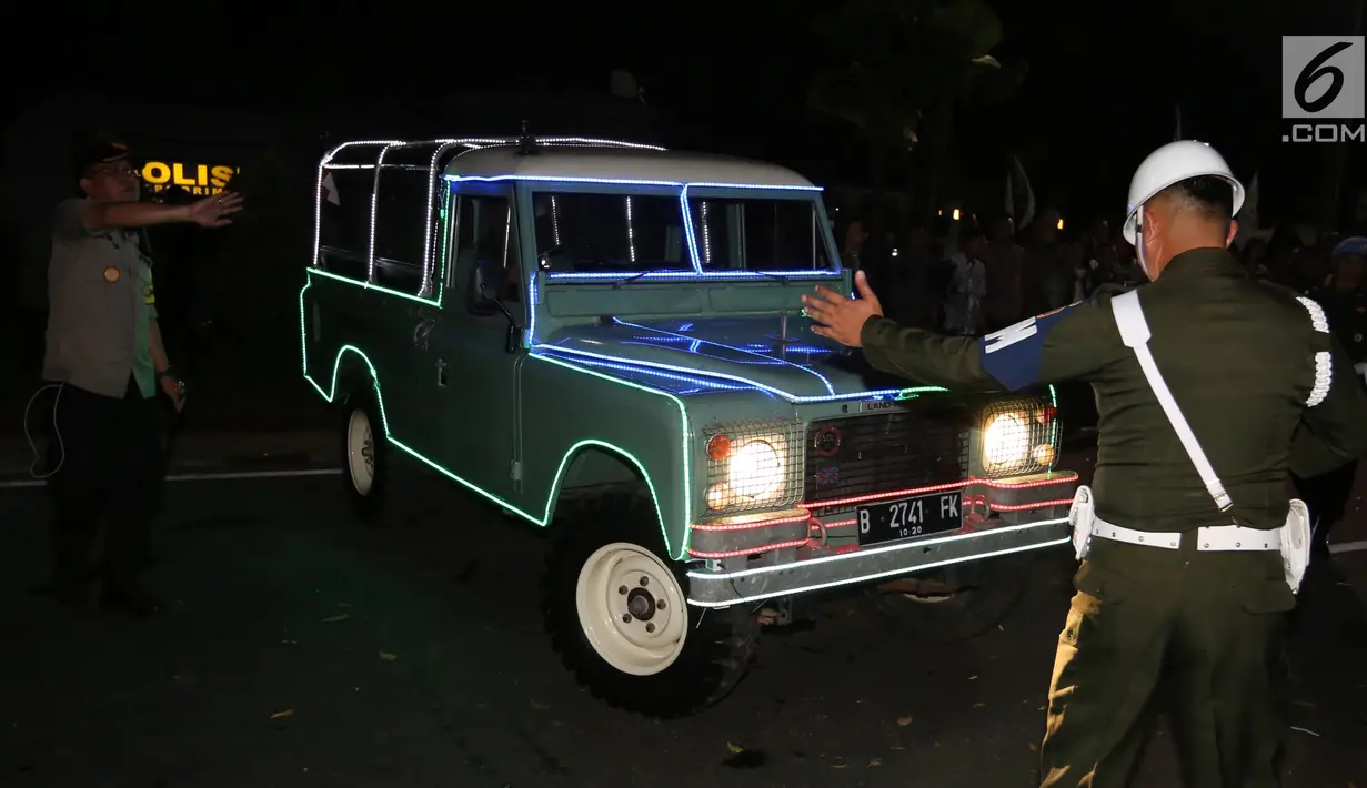 Petugas mengatur parkir mobil Land Rover klasik bak terbuka tumpangan Jokowi-Ma`ruf di gedung KPU Pusat, Jakarta, Jumat (21/9). Jokowi-Ma`ruf ke KPU untuk mengambil nomor urut Pilpres pasangan Capres dan Wapres 2019- 2024. (Liputan6.com/Fery Pradolo)