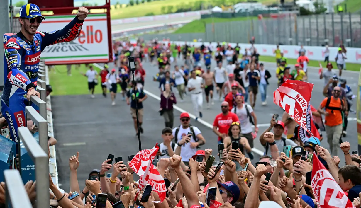Pembalap Ducati Lenovo, Francesco Bagnaia melakukan selebrasi dengan para penggemarnya usai memenangi balapan MotoGP Italia di Mugello, 2 Juni 2024. (Marco BERTORELLO/AFP)