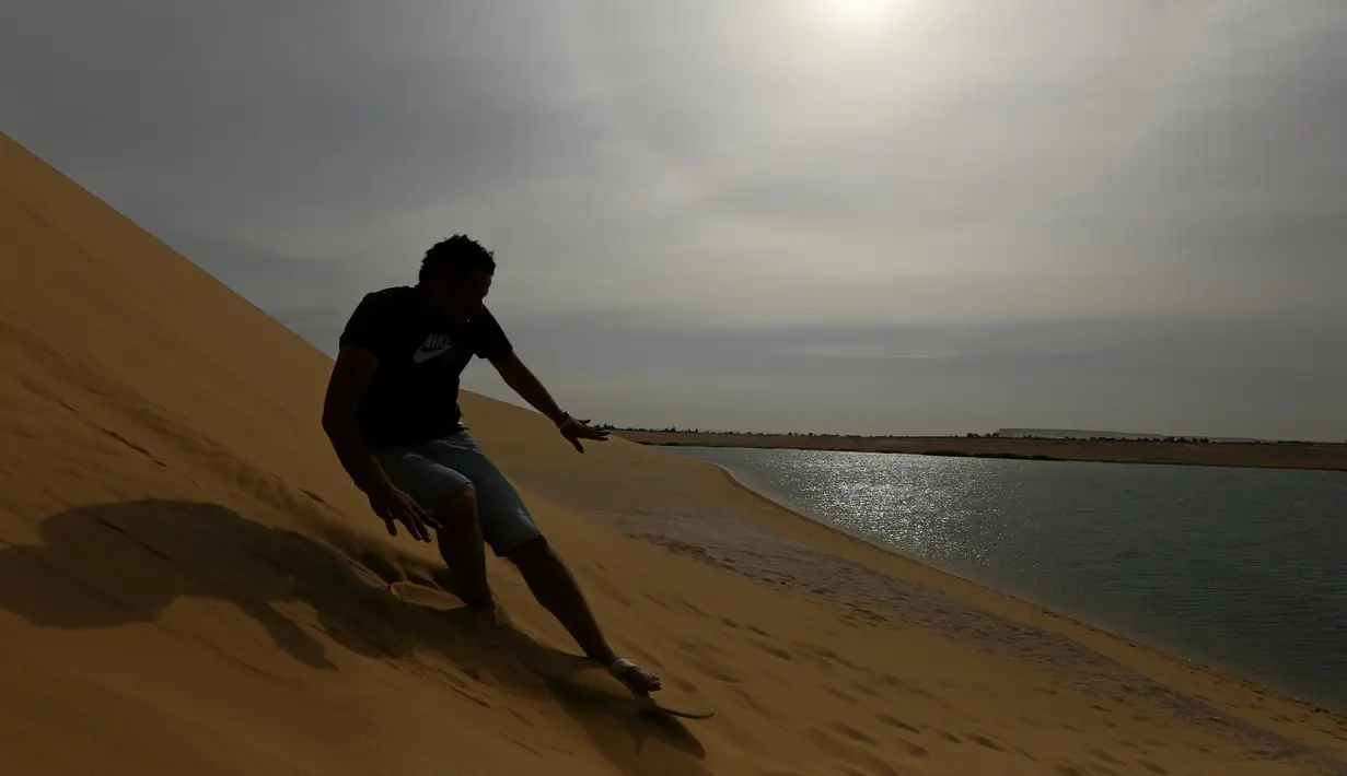 Seorang pria berseluncur menggunakan papan sandboards di gurun pasir Wadi el-Rayan Fayoum, Mesir (18/11). Sandboarding ini hampir sama dengan snowboarding, yang membedakan adalah medannya yakni di pasir. (Reuters/Mohamed Abd El Ghany)