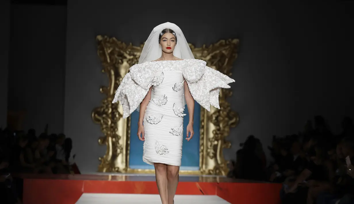 Model Gigi Hadid berjalan di catwalk memakai koleksi Moschino Spring-Summer 2020 selama pekan mode di Milan, Italia (19/9/2019). Gigi tampil anggun dengan sentuhan apik pada balutan gaun pengantin berwarna putih untuk showcase unik yang terinspirasi oleh Alice In Wonderland. (AP Photo/Luca Bruno)