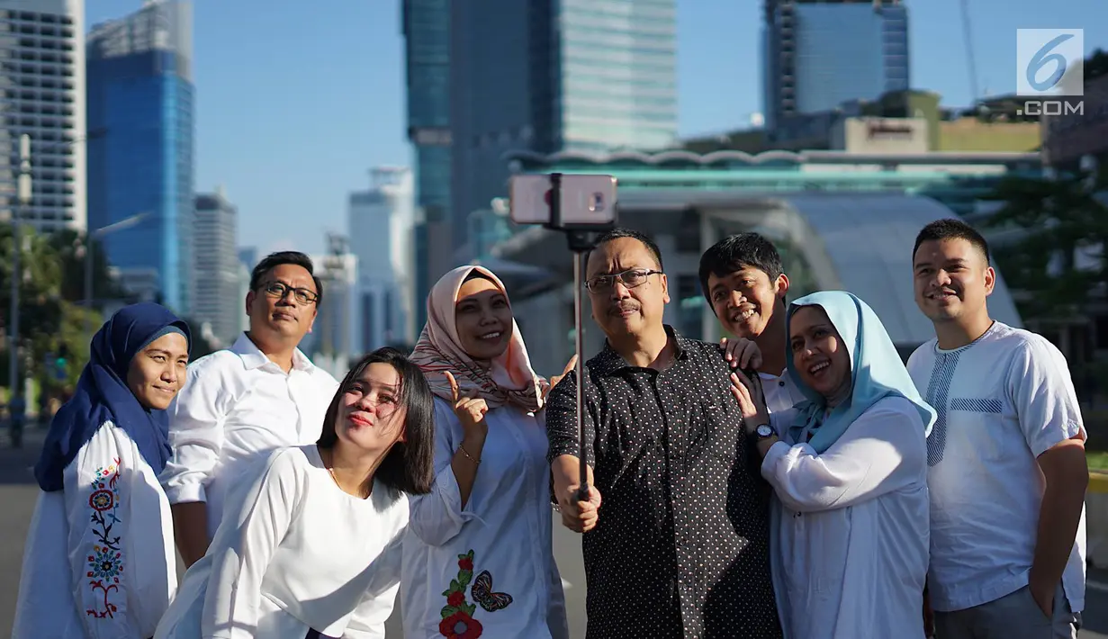 Sejumlah orang berswafoto dengan latar belakang Jalan MH Thamrin yang masih ditutup oleh aparat keamanan di Jakarta, Jumat (24/5/2019). Ditutupnya Jalan MH Thamrin terkait unjuk rasa menolak hasil Pemilu 2019 dimanfaatkan sebagian warga untuk berfoto. (Liputan6.com/Immanuel Antonius)