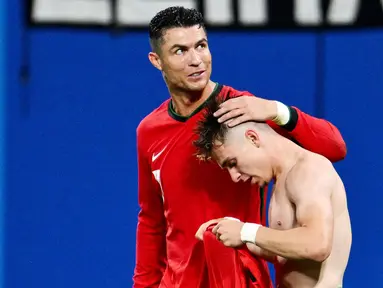 Pemain Portugal, Cristiano Ronaldo, memberikan selamat kepada Francisco Conceicao yang telah mencetak gol ke gawang Republik Ceko dalam duel matchday 1 Grup F Euro 2024, Rabu (19/6/2024). Portugal menang dengan skor 2-1. (AFP/Christophe Simon)