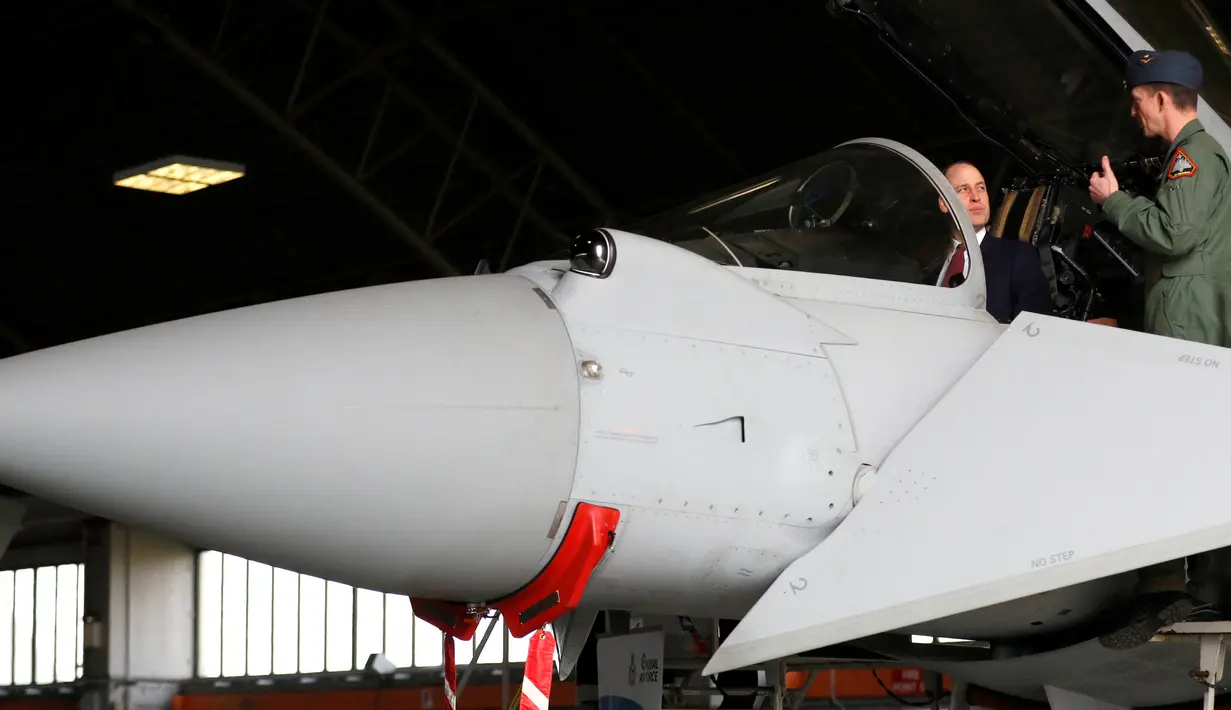 Pangeran William berbicara dengan seorang pilot jet Eurofighter Typhoon saat berkunjung ke RAF Coningsby di Lincolnshire, Inggris, Rabu (7/3). Keberadaan Typhoon untuk menyaingi pesawat F/A-18 Hornet buatan Amerika Serikat. (PHIL NOBLE/POOL/AFP)