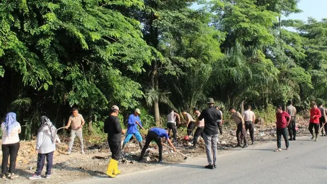 Personel Polda Riau memungut sampah di pinggir jalan Pekanbaru yang selama ini mencemari lingkungan.