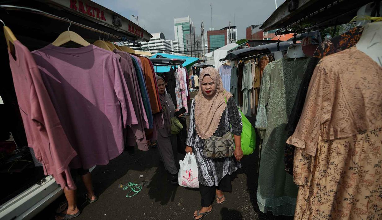 Nama Pasar Tasik sendiri muncul karena sebagian besar pedagangnya berasal dari wilayah Tasikmalaya dan Bandung, Jawa Barat. Tampak dalam foto, warga berjalan melewati toko-toko pakaian saat mereka bersiap untuk perayaan hari raya Idul Fitri di salah satu pasar musiman di Jakarta, Senin 9 Maret 2026. (AP Photo/Achmad Ibrahim)