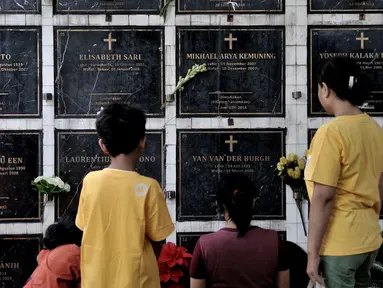 Keluarga berdoa saat berziarah ke salah satu makam bersusun atau kolumbarium di kompleks pemakaman Paroki Gereja St Servatius, Kampung Sawah, Bekasi, Jawa Barat, Kamis (26/12/2019). Kolumbarium setinggi dua meter tersebut dibangun oleh pengelola sejak awal 2018. (merdeka.com/Iqbal Nugroho)