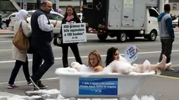 Pejalan kaki melihat aksi kampanye aktivis wanita dari PETA yang mandi dengan busa di Jalan Paulista di Sao Paulo, Brasil, Selasa (2/8). Aksi itu untuk mengajak masyarakat beralih ke pola makan vegetarian. (REUTERS/Paulo Whitaker)