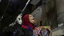 Seorang mesaharati Hajja Dalal (46) membangunkan warga untuk sahur saat bulan suci Ramadan di Kairo, Mesir, Rabu (29/4/2020). Untuk membangunkan orang sahur, seorang mesaharati biasanya akan memukul drum yang disebut dengan baza. (AP Photo/Nariman El-Mofty)