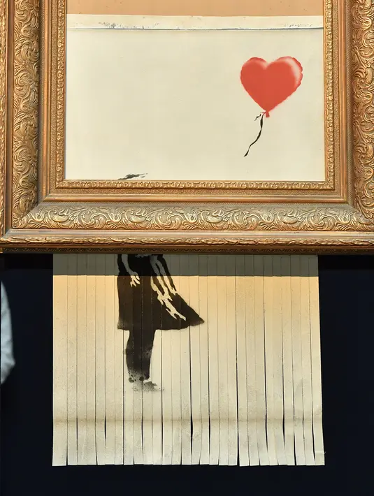 Sebuah lukisan karya seniman Bansky berjudul "Girl with Balloon" di rumah lelang Sotheby London, 12 Oktober 2018. Lukisan yang memiliki nama baru 'Love is in the Bin' tersebut diperlihatkan ke hadapan publik  pada akhir pekan lalu. (BEN STANSALL/AFP)