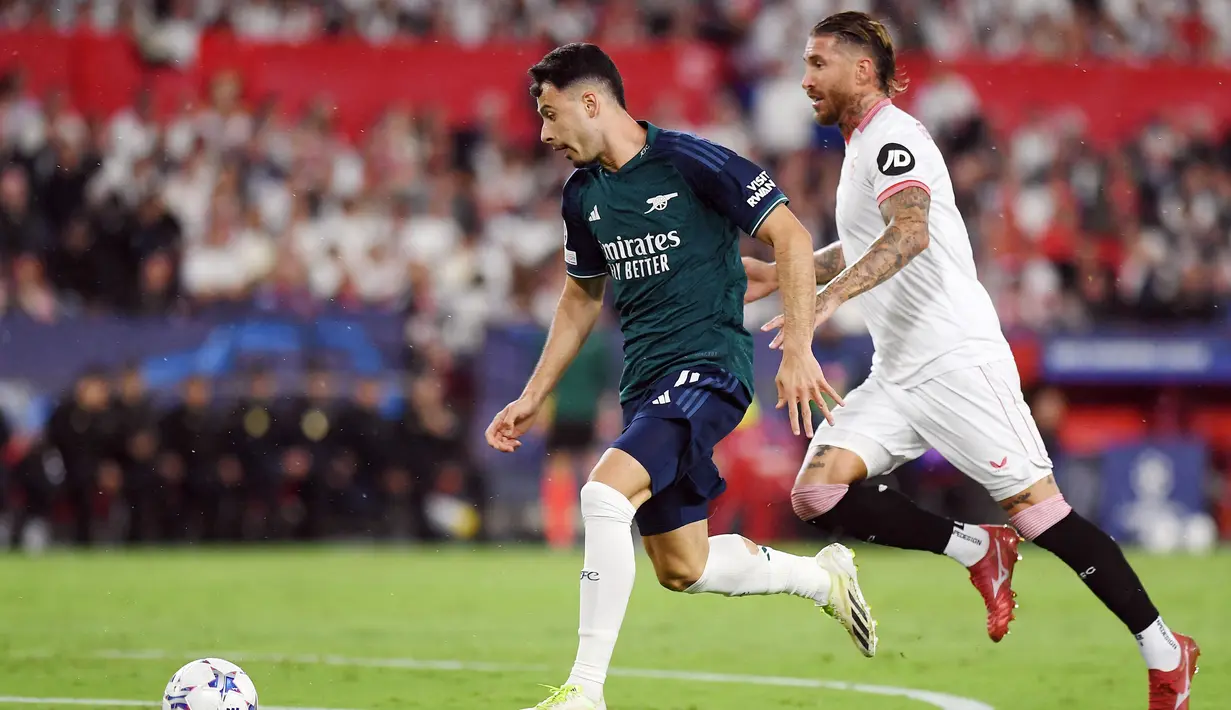 Pemain Sevilla, Sergio Ramos, berusaha mengejar pemain Arsenal, Gabriel Martinelli, pada laga Liga Champions di Stadion Ramon Sanchez Pizjuan, Rabu (25/10/2023). Ramos yang sekarang sering kalah duel termasuk saat mengejar lawan. (AFP/Jorge Guerrero)