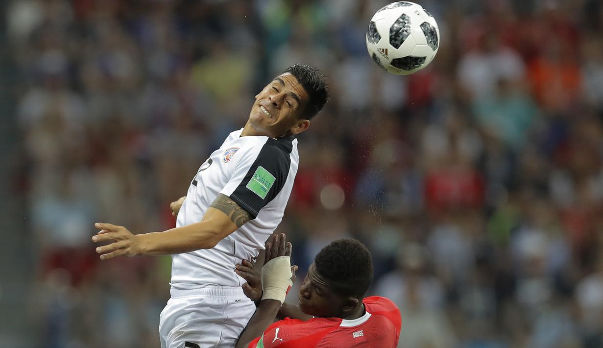 Pemain Kosta Rika, Johnny Acosta (atas) menghalau bola dari kejaran pemain pemain Swiss, Breel Embolo pada laga terakhir grup E Piala Dunia 2018 di Nizhny Novgorod Stadium, Nizhny Novgorod, Rusia, (27/6/2018). Swiss bermain imbang 2-2. (AP/Vadim Ghirda)