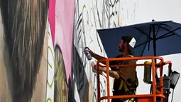 Seniman Argentina, Maximiliano Bagnasco sedang mengerjakan mural besar bergambar Lionel Messi di Wynwood, Miami, 10 Juli 2023. La Pulga akan melakukan debutnya di Inter Miami pada 21 Juli di Piala Liga. (AFP/Chandan Khanna)