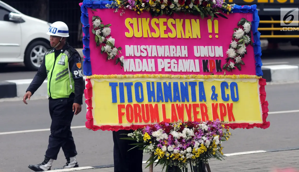 Seorang satpam berjalan dekat karangan bunga ucapan Musyawarah Umum Wadah Pegawai KPK dari Forum Lawyer KPK dan Tito Hananta di depan Gedung KPK, Jakarta, Kamis (3/5). Musyawarah ini dihadiri penyidik senior KPK Novel Baswedan. (Merdeka.com/Dwi Narwoko)