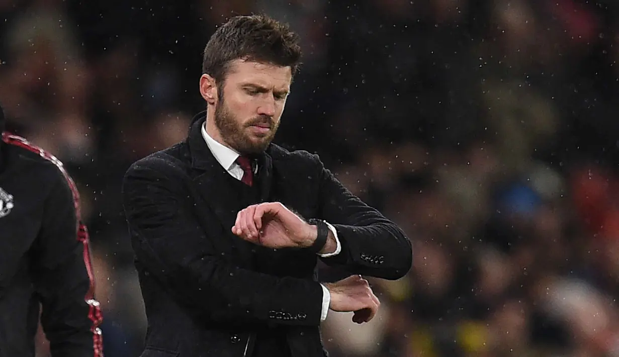 Hal itu disampaikan MU di laman resmi klub pada Rabu (14/1/2026) dini hari WIB. Tampak dalam foto, Michael Carrick saat masih menjadi pelatih sementara Manchester United melihat arlojinya selama pertandingan sepak bola Liga Premier Inggris melawan Arsenal di Old Trafford, Manchester, Inggris barat laut, pada 2 Desember 2021. (Oli SCARFF/AFP)