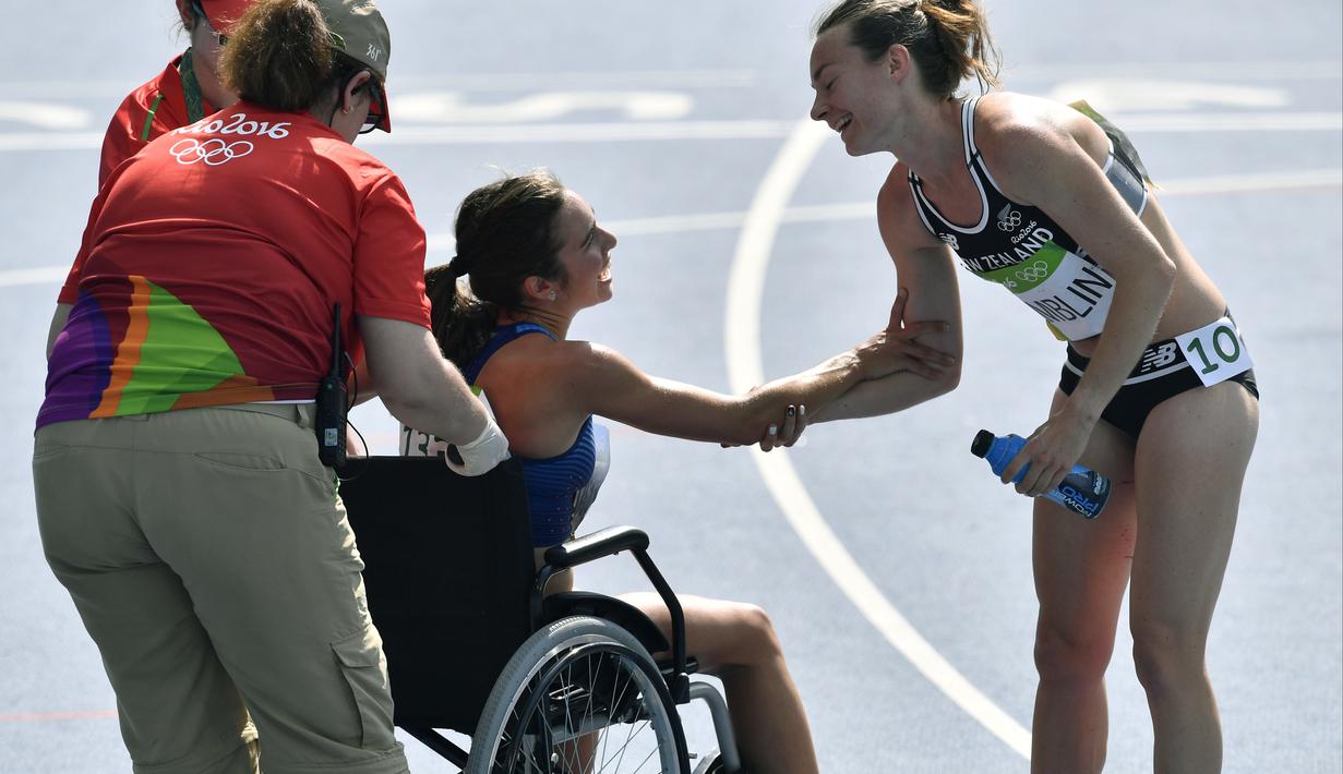 Abbey D'agostino menggunakan kursi roda karena nyeri pada kakinya setelah terjatuh dan dibantu pelari Selandia Baru, Nikki Hamblin (kanan), pada lari 5000m putri Olimpiade Rio 2016 di Olympic Stadium, Rio de Janeiro, (16/8/2016). (AP/Martin Meissner)