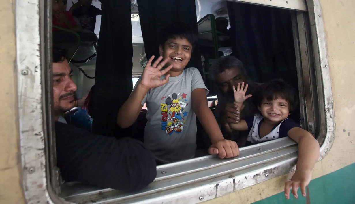 Anak-anak melambaikan tangan saat berada di kereta sebelum berangkat ke kampung halaman mereka untuk liburan Idul Fitri di stasiun kereta api di Karachi, Pakistan (2/6/2019). Idul Fitri menandai akhir bulan suci Ramadan. (AP Photo/Fareed Khan)