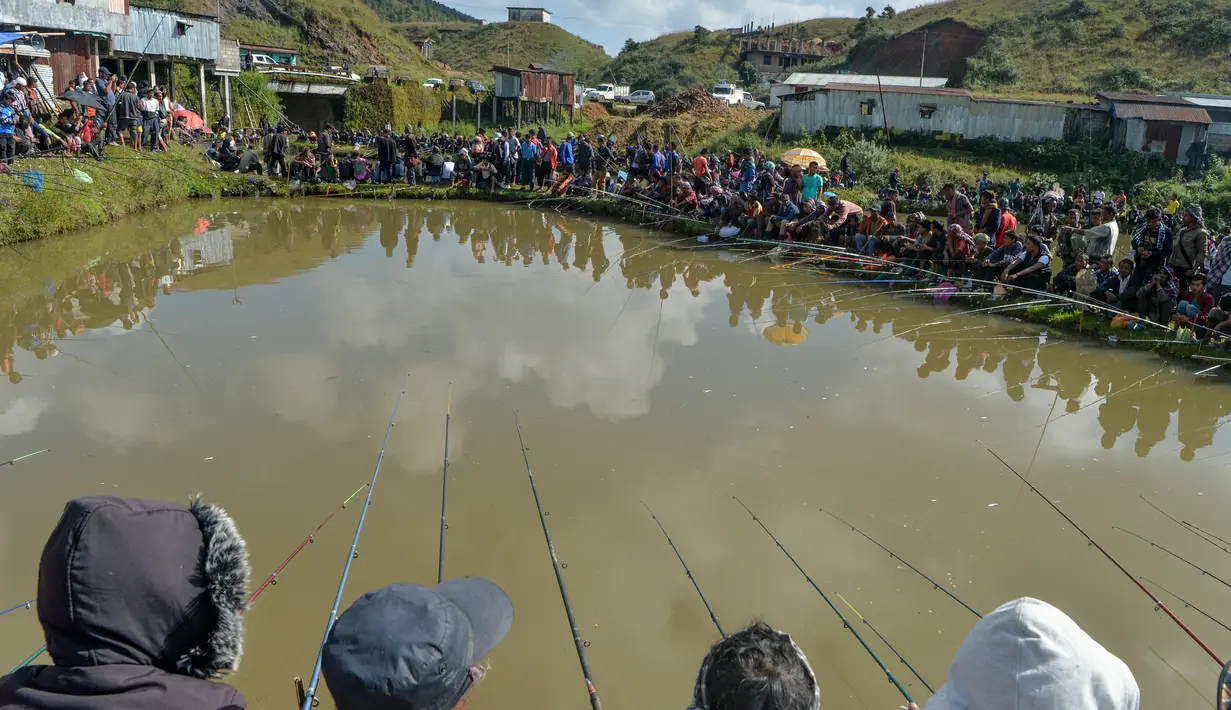 Para peserta pria berkonsentrasi dengan kailnya pada kompetisi memancing di sebuah kolam dekat desa Weilei di Negara Bagian Meghalaya, timur laut India, Sabtu (21/9/2019). Ratusan peserta berpartisipasi dalam kompetisi yang memperebutkan sejumlah hadia tersebut. (DIPTENDU DUTTA / AFP)