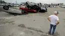 Seorang pekerja melihat-lihat mobil yang rusak akibat tornado di sebuah dealer di Jefferson City, Missouri, AS, Kamis (23/5/2019). Tornado juga menghantam ibu kota negara bagian, membawa hujan lebat, hujan es, angin, dan kilat. (AP Photo/Charlie Riedel)